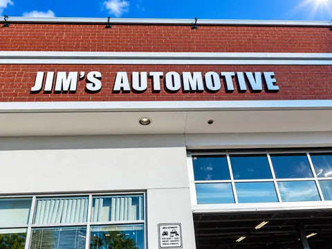 Close-up of the JIM'S AUTOMOTIVE lettering on the brick facade above the shop windows