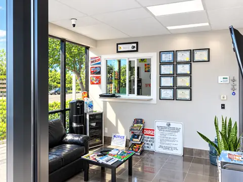 Bright customer lobby at Jim's Automotive with a leather couch, a service window and framed documents on the wall