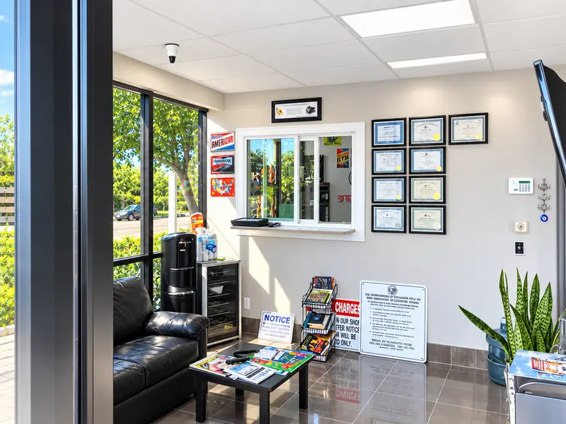 Bright customer lobby at Jim's Automotive with a leather couch, a service window and framed documents on the wall