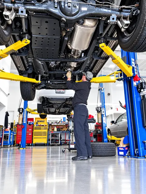 Technician inspecting the underside of a vehicle raised on a lift at Jim's Automotive in Huntington Beach